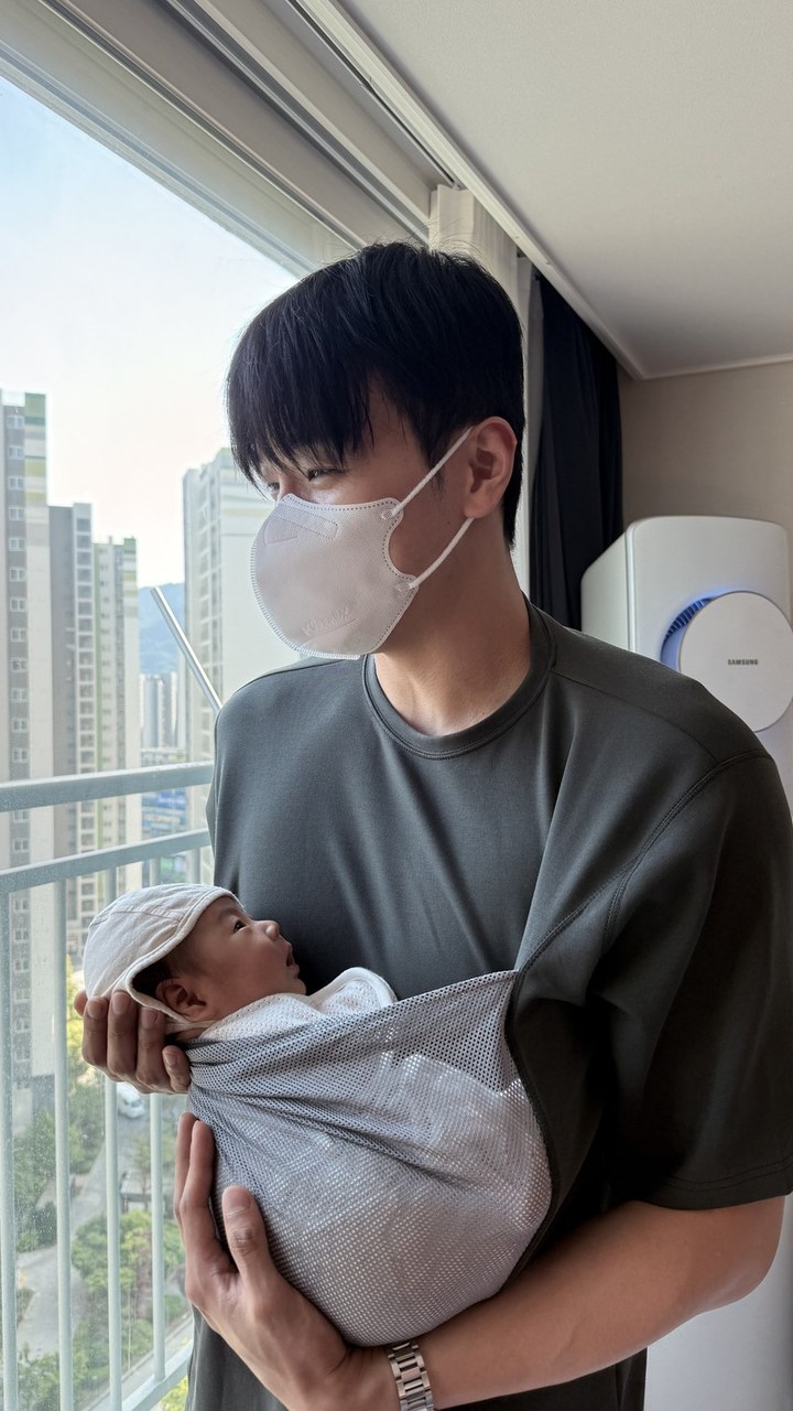 A father holding his newborn in the mesh pouch of a Horcen Hug-Me T-shirt